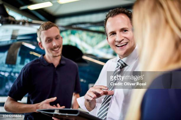 happy businessman, young woman and mechanic discussing in airplane hangar - hangar stock-fotos und bilder