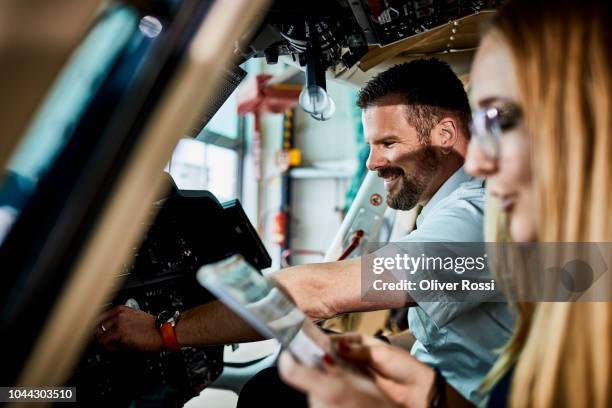 smiling instructor and young woman talking inside helicopter in airplane hangar - beard pilot stock pictures, royalty-free photos & images