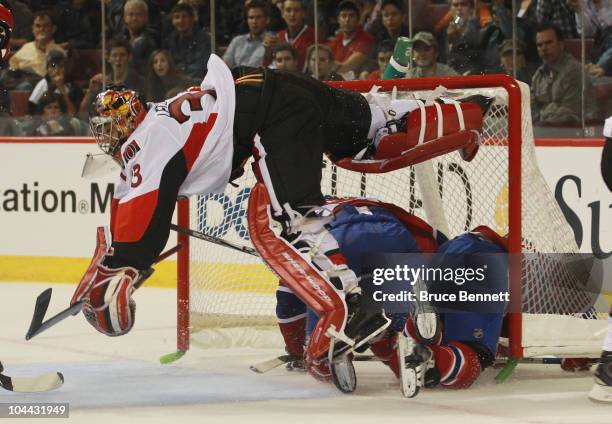 Pascal Leclaire of the Ottawa Senators is upended by David Desharnaid and Alex Henry of the Montreal Canadiens at the Bell Centre on September 24,...
