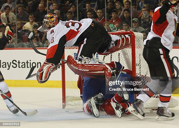 Pascal Leclaire of the Ottawa Senators is upended by David Desharnaid and Alex Henry of the Montreal Canadiens at the Bell Centre on September 24,...