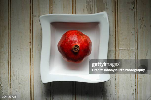 pomegranate in contemporary white bowl - square plate stock pictures, royalty-free photos & images