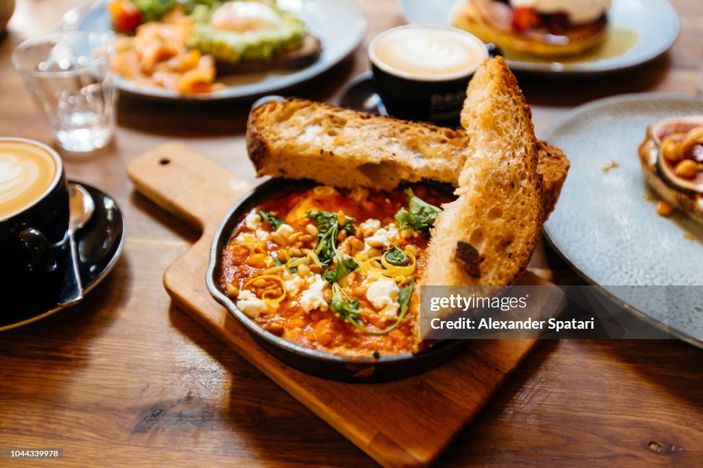 Close up of shakshuka served in cooking pan on the table in cafe