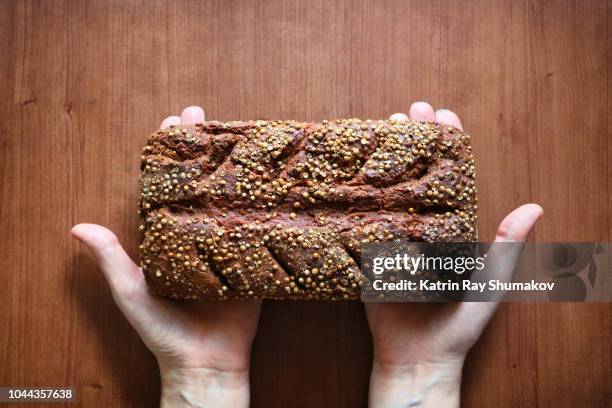 homemade rustic rye bread in hands - volkorentarwe stockfoto's en -beelden