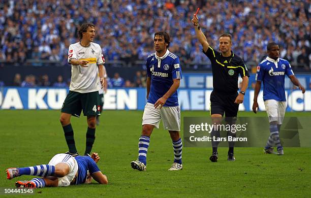 Referee Peter Gagelmann shows Roel Brouwers of Moenchengladbach the red card after a tackle against Klaas Jan Huntelaar of Schalke during the...