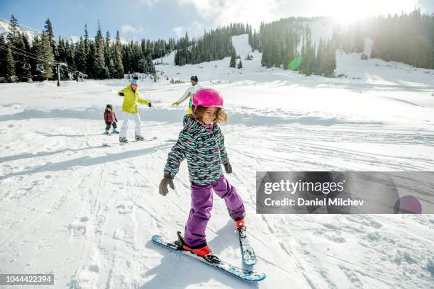 young mixed race girl laughing as she is learning how to ski with her family in colorado. - holiday resort family sunshine stock pictures, royalty-free photos & images