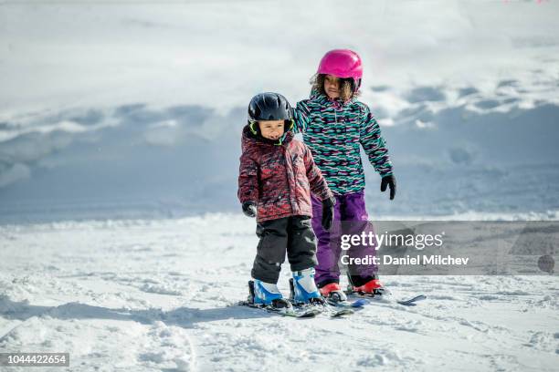 two mixed race kids having fun while skiing on a sunny day during the winter. - keystone stock pictures, royalty-free photos & images