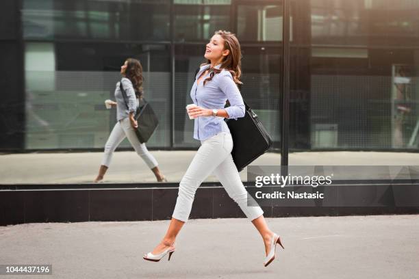 young fashionable business woman with long curly hair walking fast - business woman walking stock pictures, royalty-free photos & images