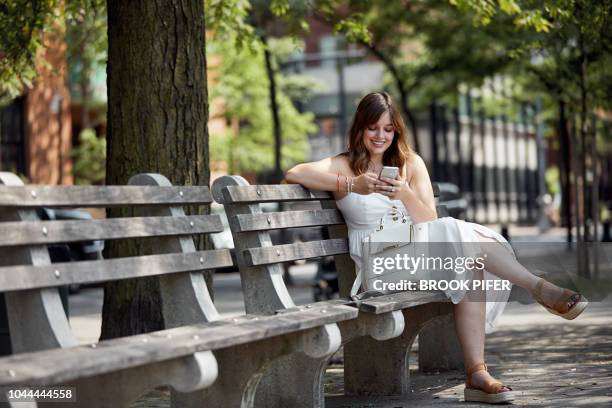 girl sitting on bench with phone - premium acess stock-fotos und bilder