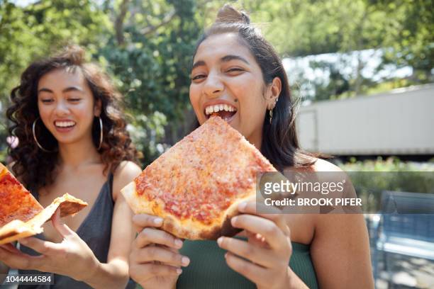 young females hanging out in city eating pizza - friends eating stock pictures, royalty-free photos & images