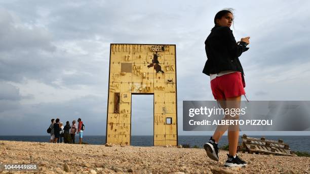 Tourist are pictured by the "Porta di Lampedusa", known as "The door of Europe", a monument to the migrants who have died in the Mediterranean,...