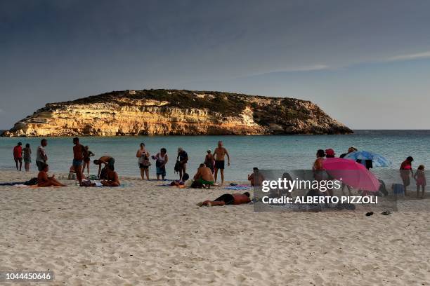 Tourists are pictured on the beach of the Isola dei Conigli in Lampedusa on September 25, 2018. - Five years after the worst shipwreck of its...