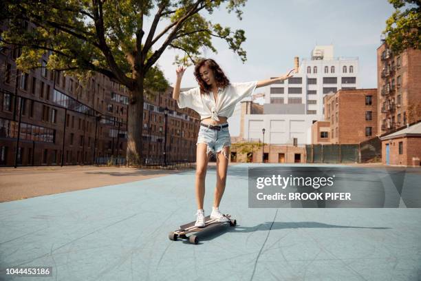 young woman in city on skateboard - building top foto e immagini stock