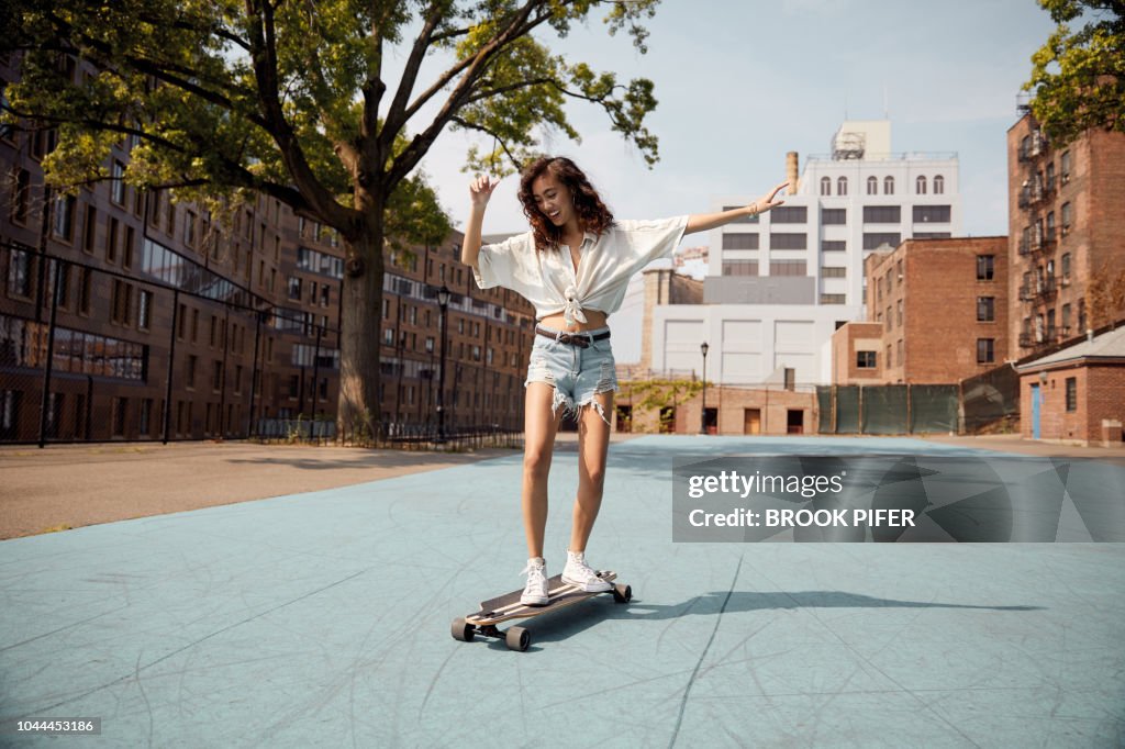 Young woman in city on skateboard