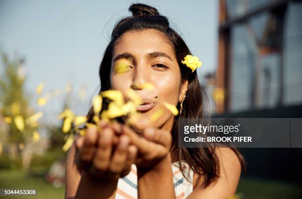 portrait of young woman blowing kiss of flowers - urban art stock-fotos und bilder