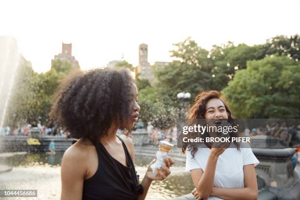 young females hanging out in city park eating ice cream - new york food stockfoto's en -beelden