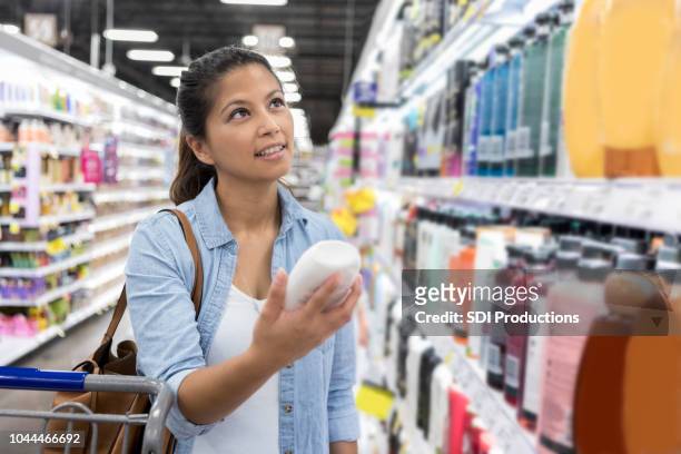 frau kauft für shampoo im supermarkt - bottle shop stock-fotos und bilder