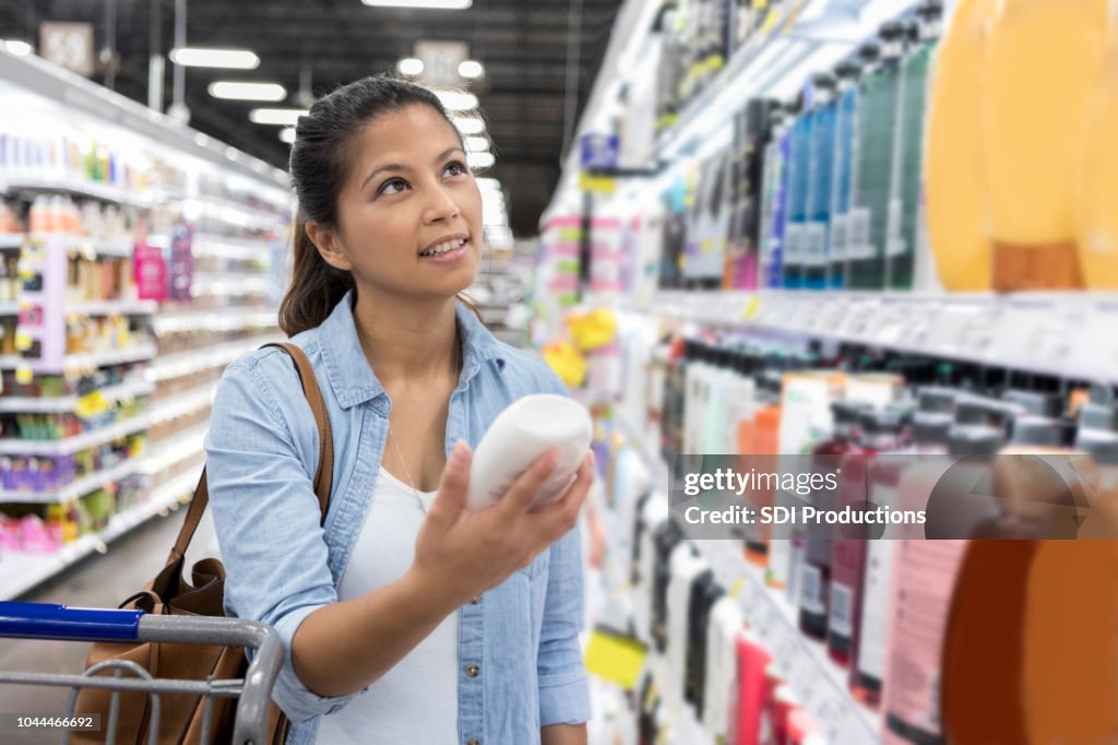 Woman shops for shampoo in supermarket