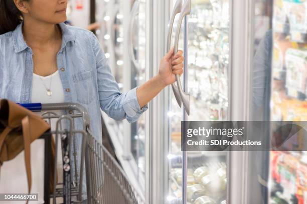 woman shops in refrigerated section in supermarket - frozen food stock pictures, royalty-free photos & images