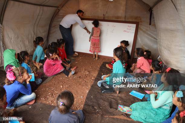 Syrian children who fled with their families from the northern countryside of Hama, attend a class at the makeshift school of "Zuhur al-Mustaqbal" in...