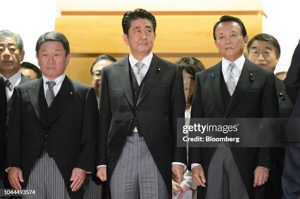 Shinzo Abe, Japan's prime minister, front row center, stands with Taro Aso, deputy prime minister and finance minister, right, and Toshimitsu Motegi,...