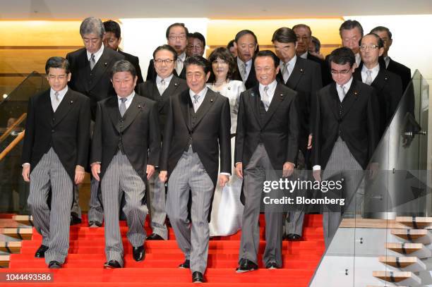 Shinzo Abe, Japan's prime minister, front row center, walks to a group photograph with his new cabinet members at the Prime Minister's official...