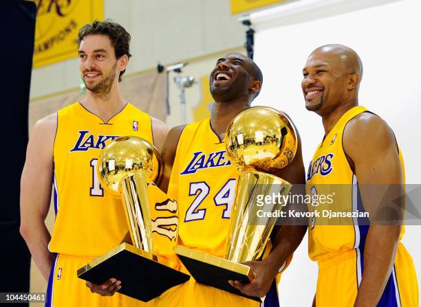 Kobe Bryant of the Los Angeles Lakers laughs as he holds two NBA Finals Larry O'Brien Championship Trophy's as he poses for a photograph with...