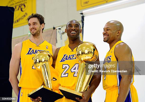 Kobe Bryant of the Los Angeles Lakers smiles as he holds two NBA Finals Larry O'Brien Championship Trophy's as he poses for a photograph with...