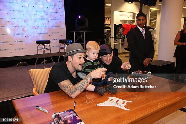 Musicians Joel and Benji Madden of the band Good Charlotte pose with two year old Calvin Lindquist at the Rosedale Macy's store on Saturday,...