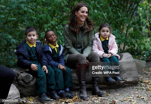 Catherine, Duchess of Cambridge sits on a log with children during a visit to Sayers Croft Forest School and Wildlife Garden on October 2, 2018 in...
