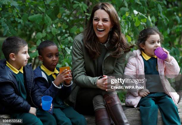 Catherine, Duchess of Cambridge sits on a log with children during a visit to Sayers Croft Forest School and Wildlife Garden on October 2, 2018 in...