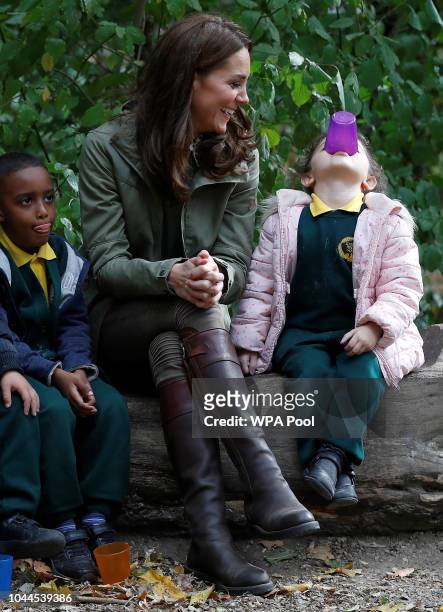 Catherine, Duchess of Cambridge sits on a log with children during a visit to Sayers Croft Forest School and Wildlife Garden on October 2, 2018 in...