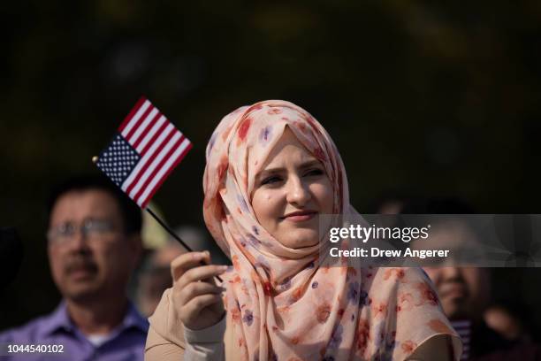 After becoming an American citizen, Suad Alnababteh waves an American flag while 'America The Beautiful' is sung during a naturalization ceremony at...