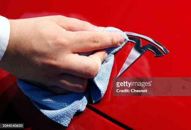 An employee cleans the logo of a Tesla Model 3 automobile during the first press day of the Paris Motor Show at the Parc des Expositions at the Porte...