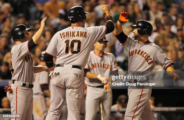 Cody Ross of the San Francisco Giants is welcomed home by Travis Ishikawa and Mike Fontenot who scored on his three run home run off of Esmil Rogers...