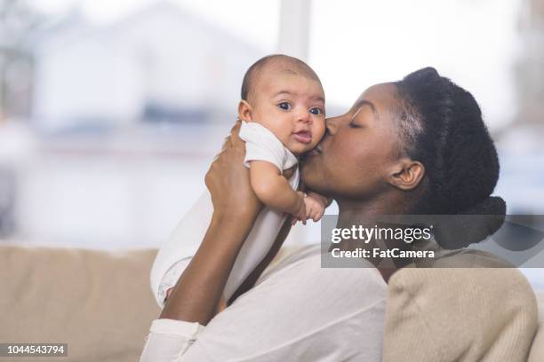 prachtige afrikaanse amerikaanse moeder houdt pasgeboren baby in de woonkamer - mothers babies stockfoto's en -beelden