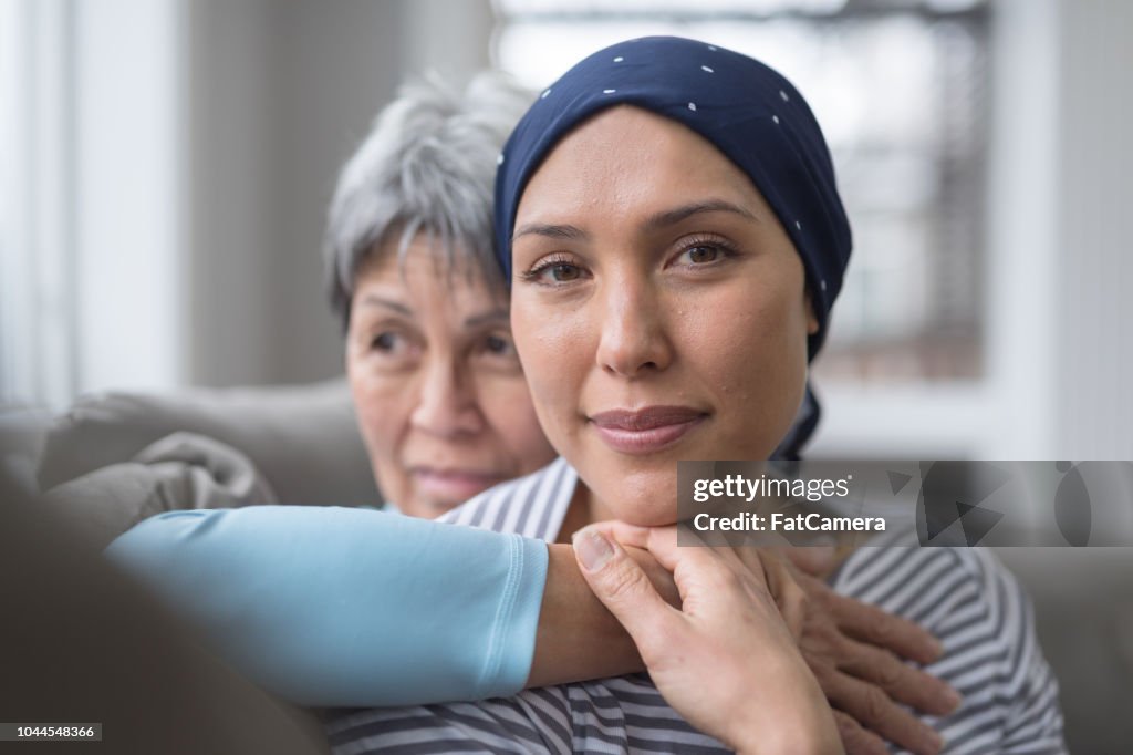 An Asian woman in her 60s embraces her mid-30s daughter who is battling cancer