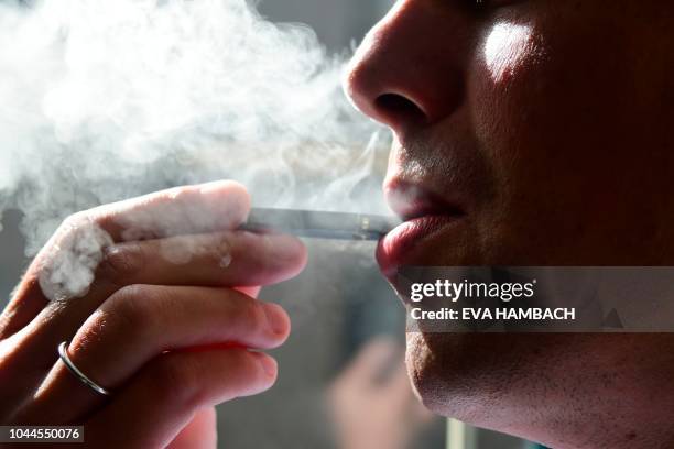 An illustration shows a man exhaling smoke from an electronic cigarette in Washington, DC on October 2, 2018. - In just three years, the electronic...