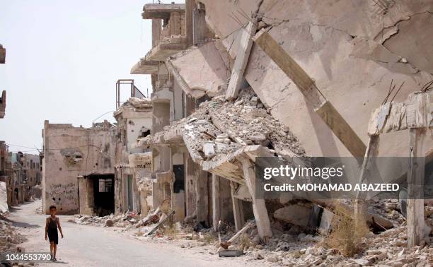 Syrian child walks past the rubble of destroyed buildings in an opposition-held neighbourhood of the southern city of Daraa on October 2, 2018.