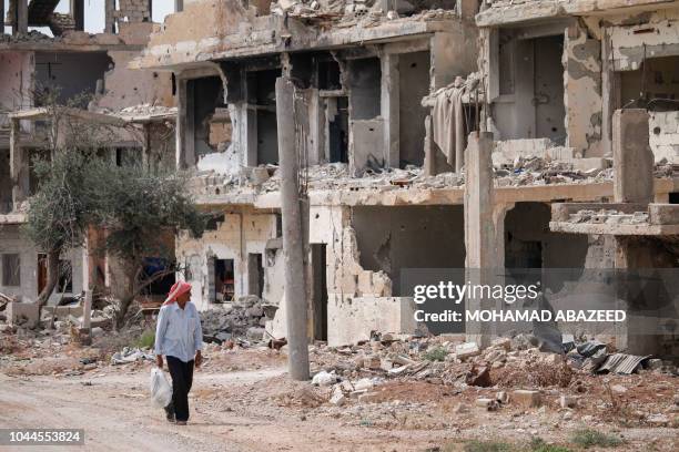 Syrian walks past the rubble of destroyed buildings in an opposition-held neighbourhood of the southern city of Daraa on October 2, 2018.