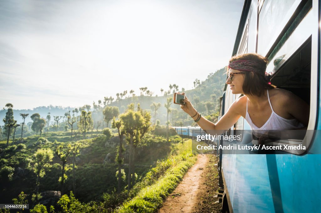 Young woman classic Ella train ride, taking smart phone pic