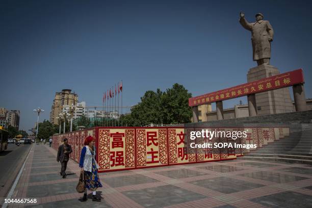 Uyghur woman walks pass a statue of Mao Zedong in the People's Park in Kashgar city, northwestern Xinjiang Uyghur Autonomous Region in China. Kashgar...
