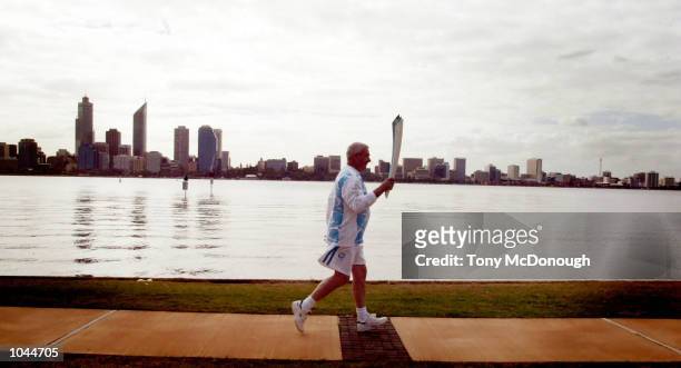 Ray Andrews, former manager of the Australian shooting team that won gold in the Atlanta Olympics carries the Olympic Torch along The Esplanade in...