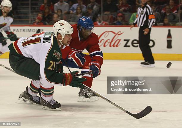 Kyle Brodziak of the Minnesota Wild shoots the puck as P.K. Subban of the Montreal Canadiens checks him at the Bell Centre on September 26, 2010 in...