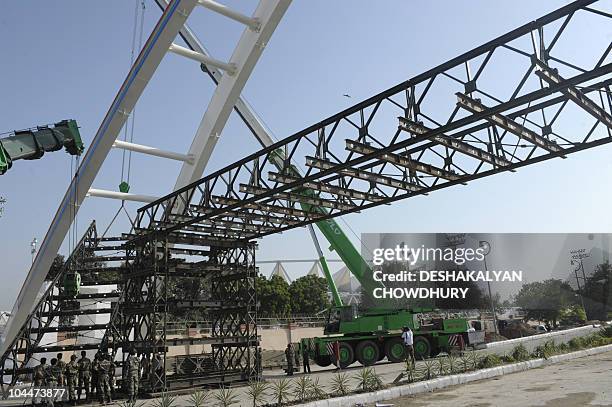 Indian soldiers reconstruct a collapsed footbridge outside Jawaharlal Nehru Stadium, the main Commonwealth Games venue, in New Delhi on September 27,...