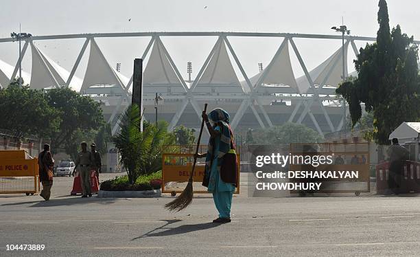 An Indian sweeper cleans the road beside the Jawaharlal Nehru Stadium, the main Commonwealth Games venue, in New Delhi on September 27, 2010....