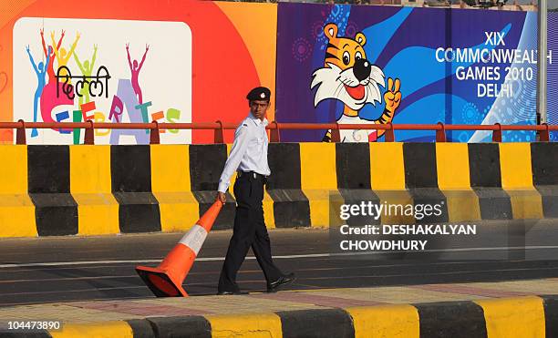 An Indian policeman carries a road divider to identify a dedicated lane for the Commonwealth Games, near the Jawaharlal Nehru Stadium, the main...