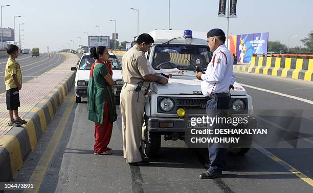 Indian traffic policemen writes a traffic ticket for a car that drove on a lane exclusively catering to athletes and the delegations during the...