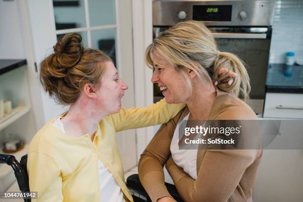 mother relaxing with disabled daughter at home - teenager cerebral palsy stock pictures, royalty-free photos & images