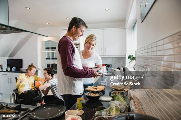 一方、障害者の娘を気遣う息子のお弁当を作って親 - middle aged couple cooking ストックフォトと画像
