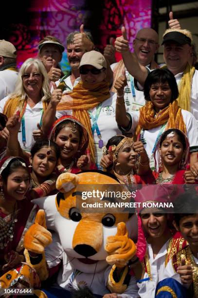 Commonwealth Games Norfolk Island team members have their picture taken with Games mascot Shera the Tiger and Indian performers who danced during the...